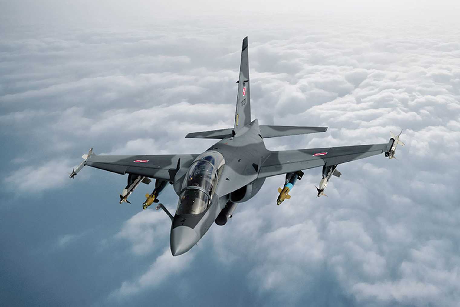 Nigerian Air Force fighter jet in flight above clouds, fully armed